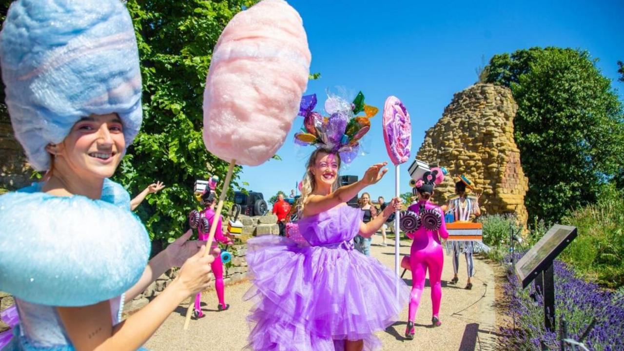 Pontefract Liquorice Festival parade. People are dressed in bright colours and are carrying large pretend sweets.