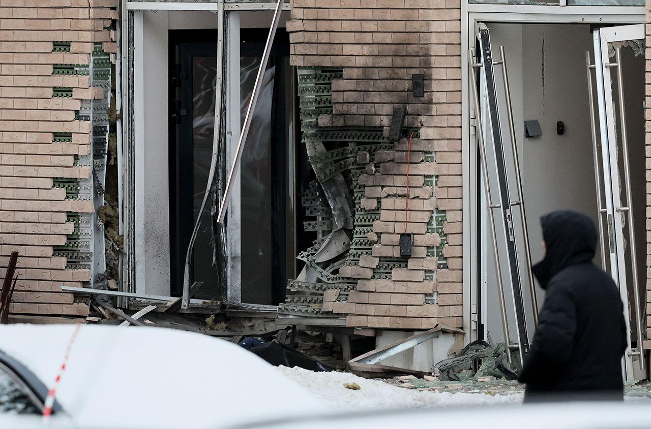 Damage to brickwork and windows is seen on the outside of an apartment block in Moscow as a person in a hooded jacket looks on, taken 17 December.