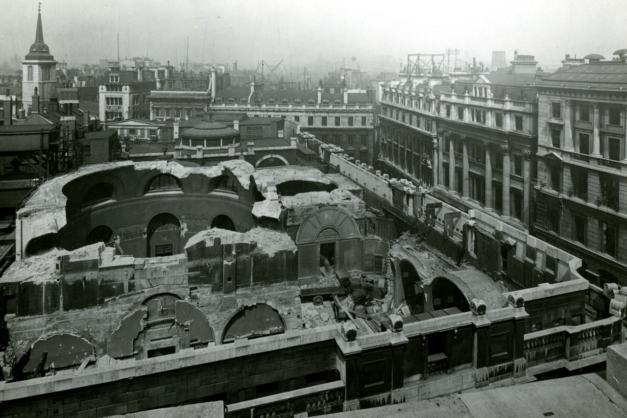 Black and white aerial photo of parts of original bank demolished with roofs missing from the building