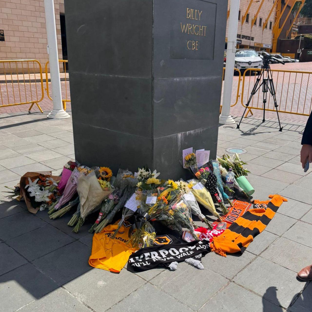 Bunches of flowers and several orange and black Wolves scarves are placed at the base of a statue outside Molineux Stadium in Wolverhampton.