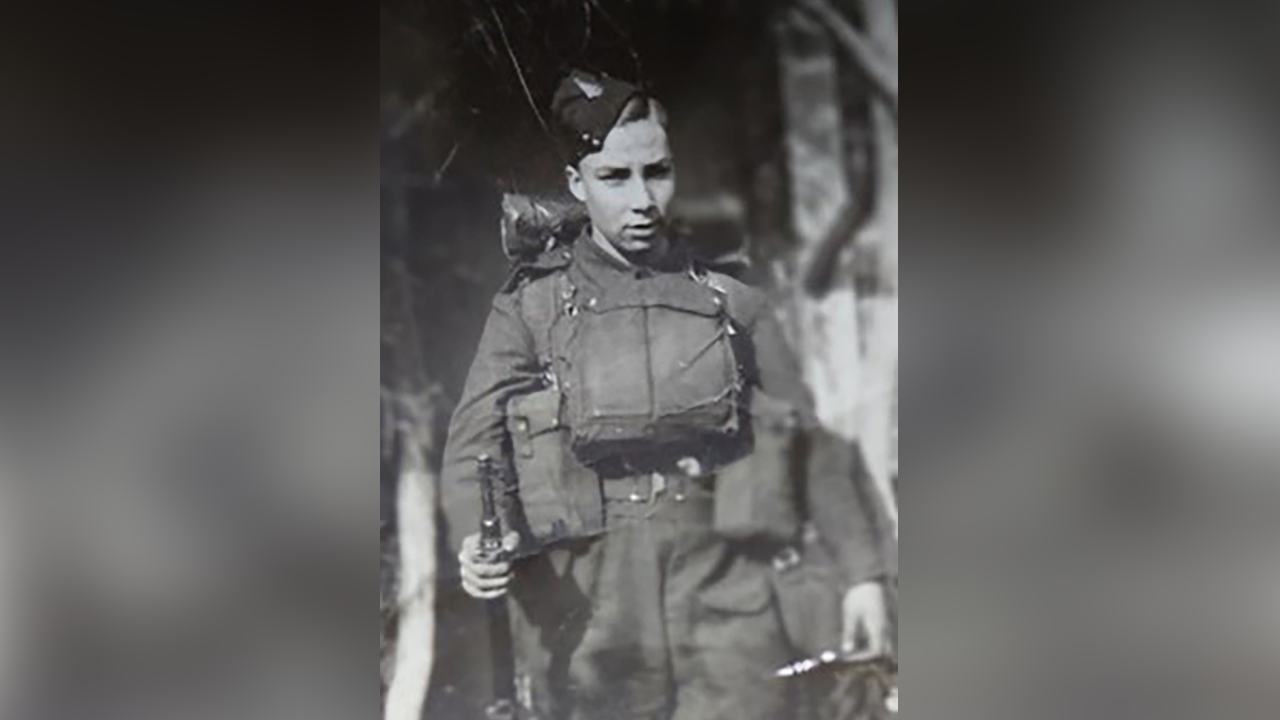 A young boy in army uniform pictured in black and white.