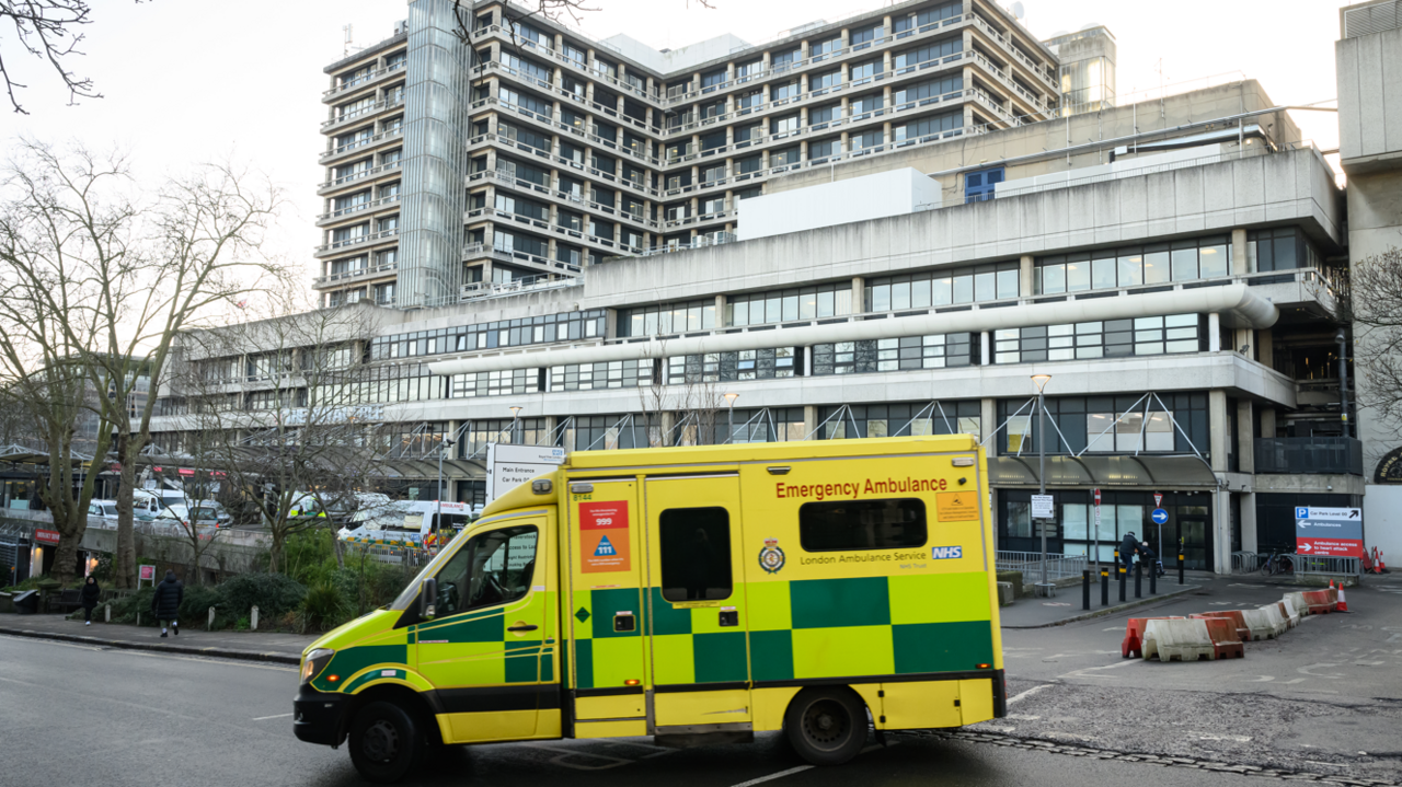 A file image showing the entrance to the Royal Free Hospital in Camden, a multi-storey concrete building, with a yellow and green ambulance turning in front of it