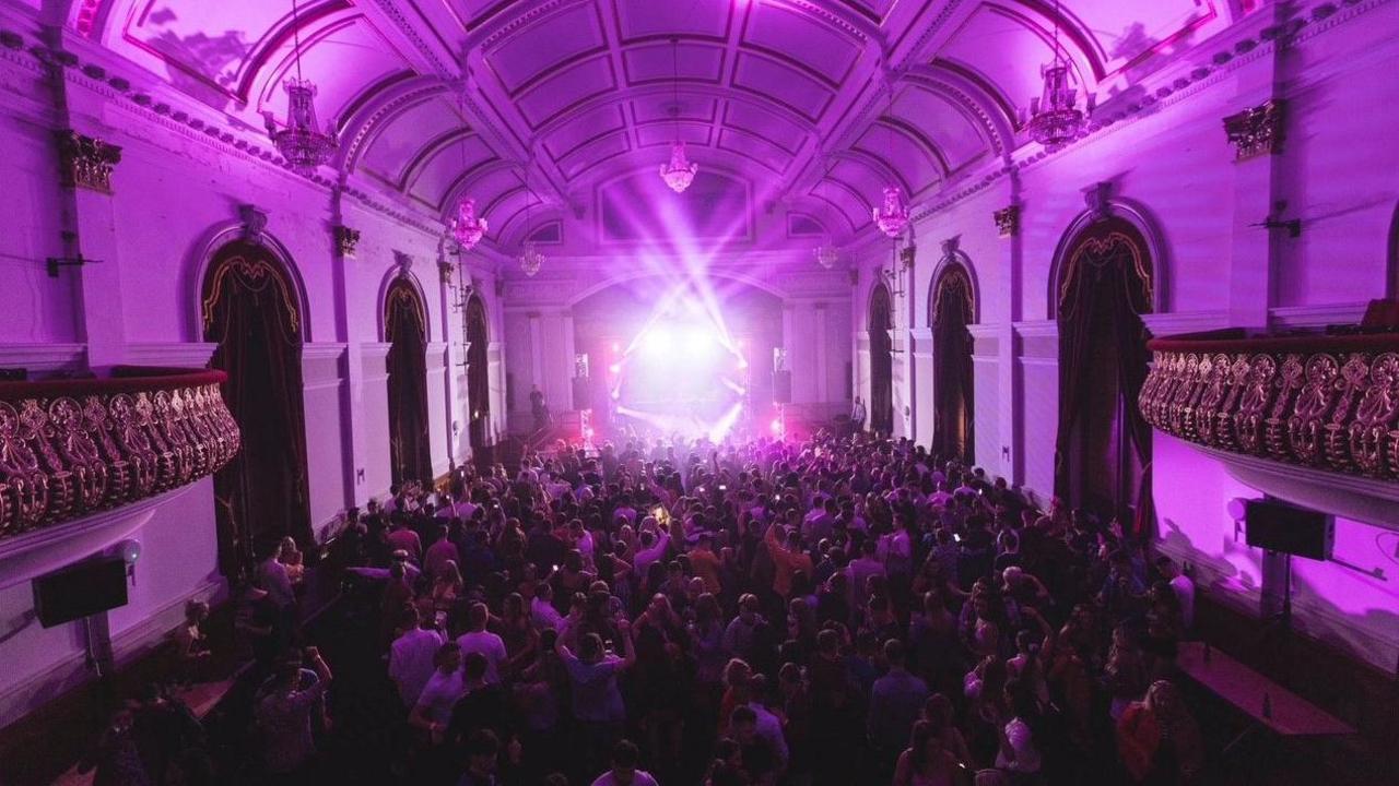 A large crowd is seen enjoying music while a light show is visible on stage