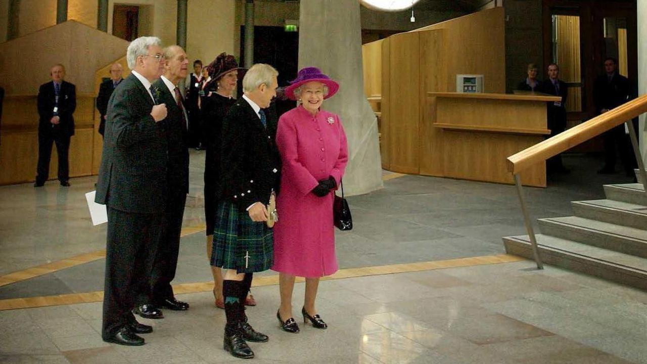 Showing the Queen around the new Holyrood building  in 2004. Sir George is in HIghland dress and the queen in a pink coat and hat. The Duke of Edinburgh can be seen in the background.
