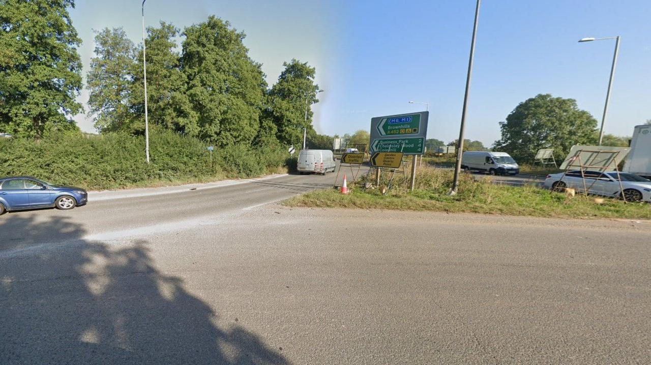An exit on a roundabout, signposted Brownhills A452. A blue car on the left is about to drive onto the road, while on the right of the photo vehicles are preparing to leave the A452.