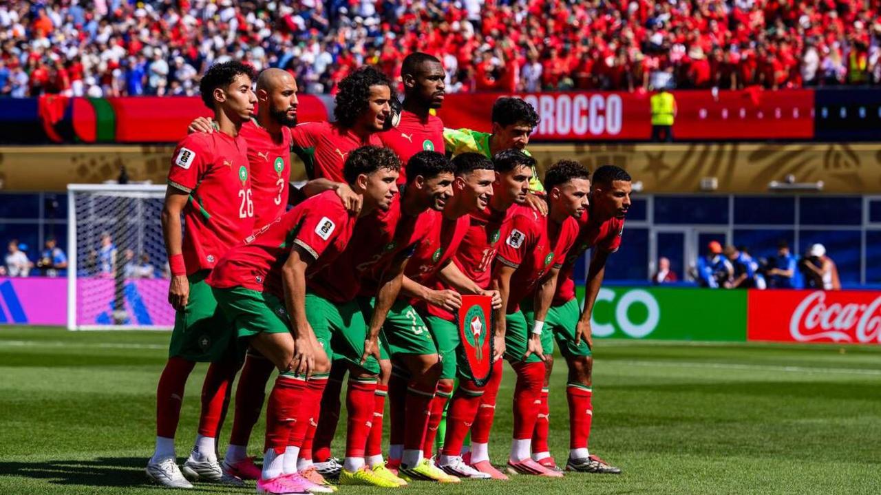 Los jugadores de Marruecos se alinean para una foto previa al partido con sus aficionados de fondo.
