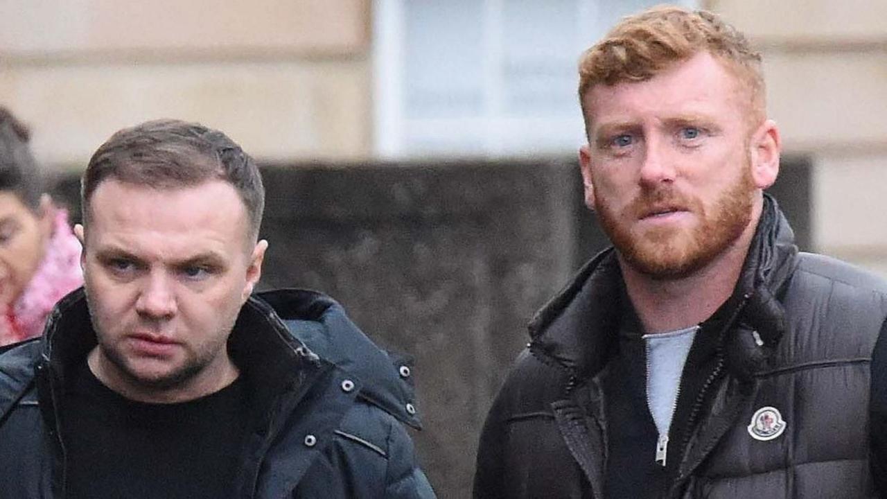 Eddie Lyons Jr (left) and Ross Monaghan (right) wearing dark clothing. Monaghan has red hair and is looking right at the camera. Lyons Jnr is looking off camera and has dark hair.