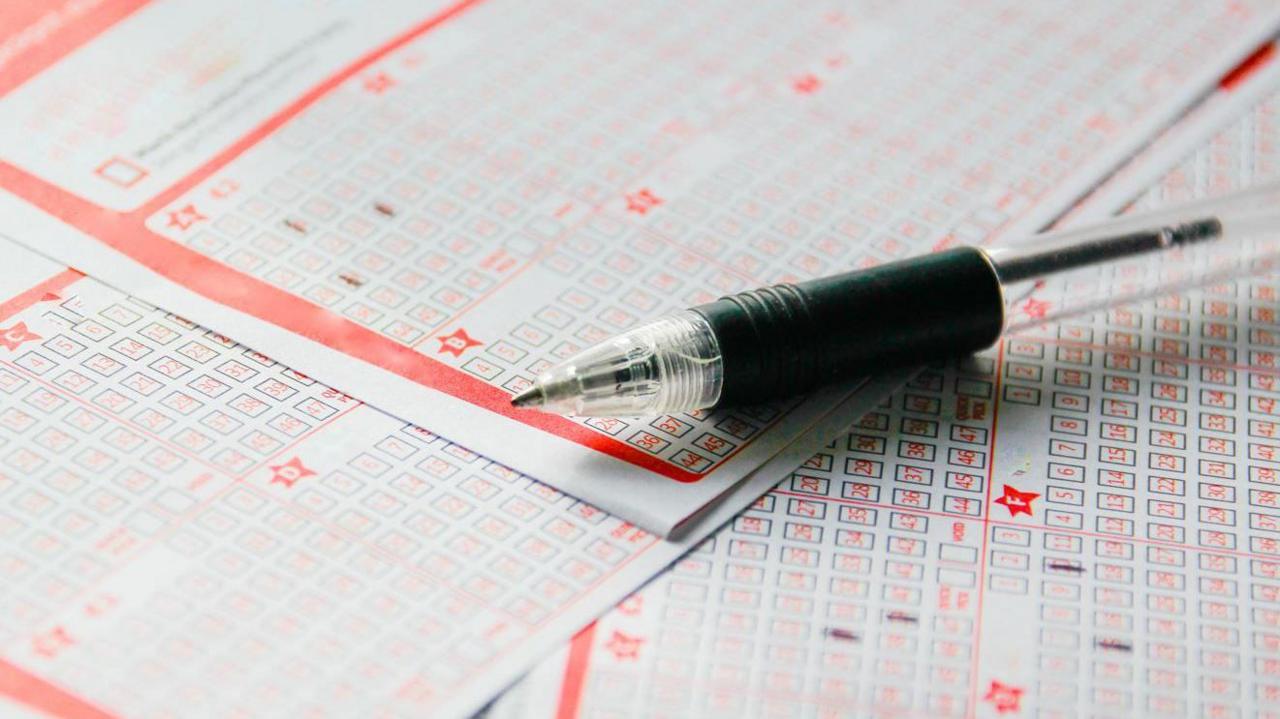 A pen sits on top of a number of lottery tickets.