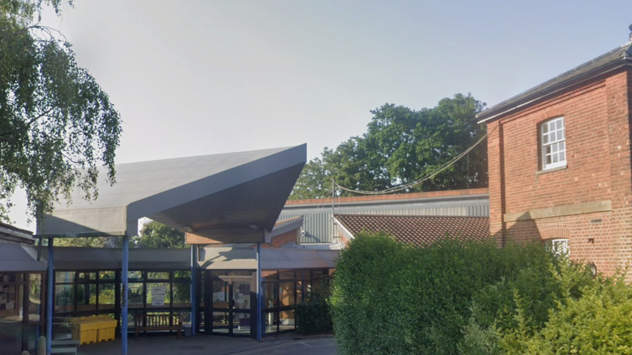 A view of the main entrance of the Dorking Community Hospital, a red brick and grey concrete and glass modern building.