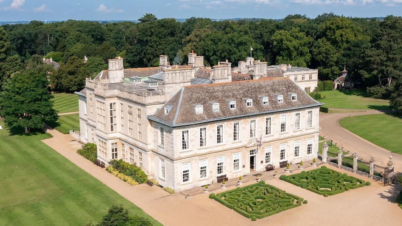 An aerial view of the grand country house at Stapleford Park, with two manicured mazes in front and manicured lawns around it