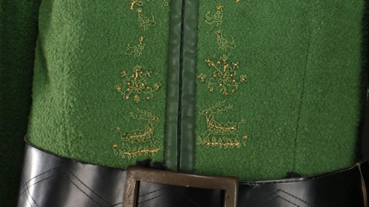 A close up of the green tunic showing gold stitching