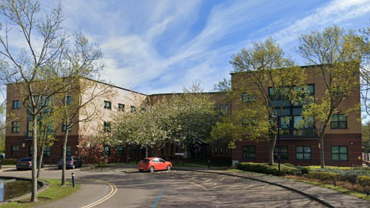 A Google Streetview screenshot of Doxford International Business Park in Sunderland. A road leads to a large office block with parking spaces at the front.