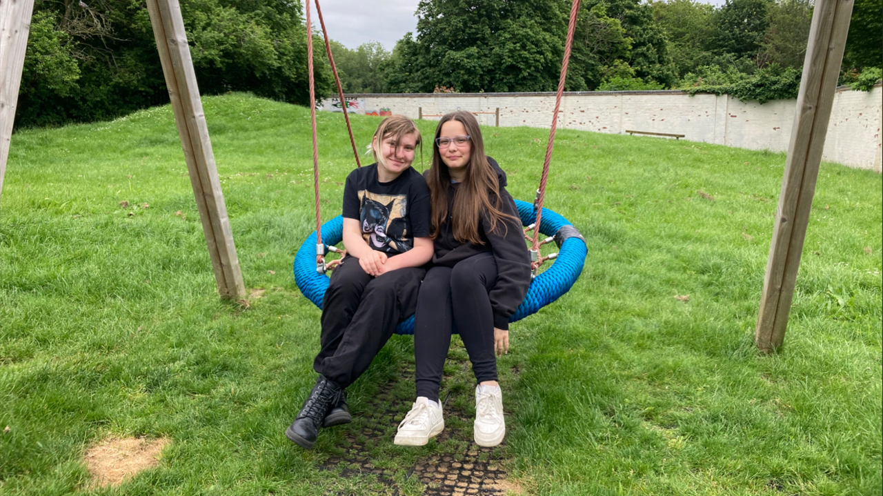 Evie and Evie sitting next to each other on a big swing in the garden of Crofts Corner