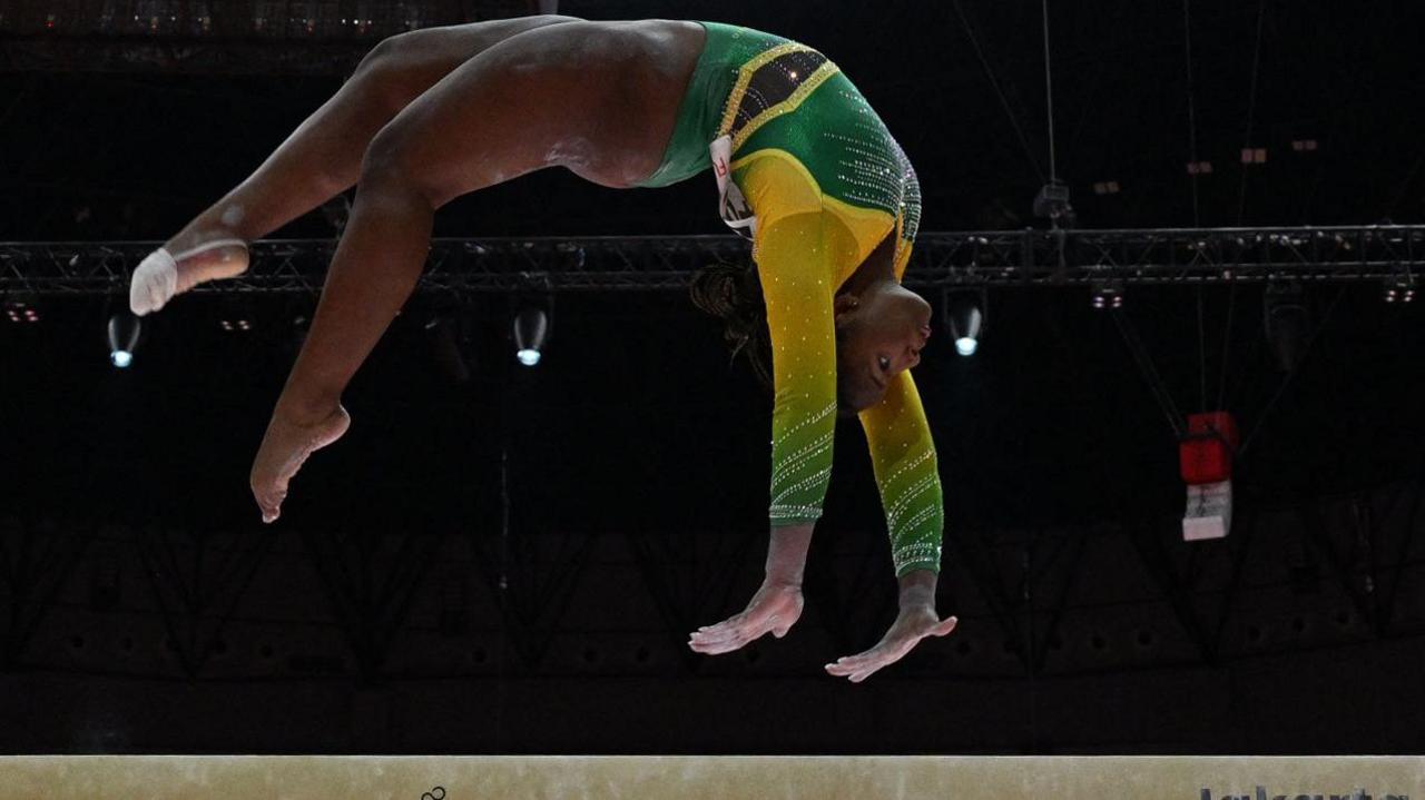 jamaican Danyella Holmes athlete doing a backflip on the beam