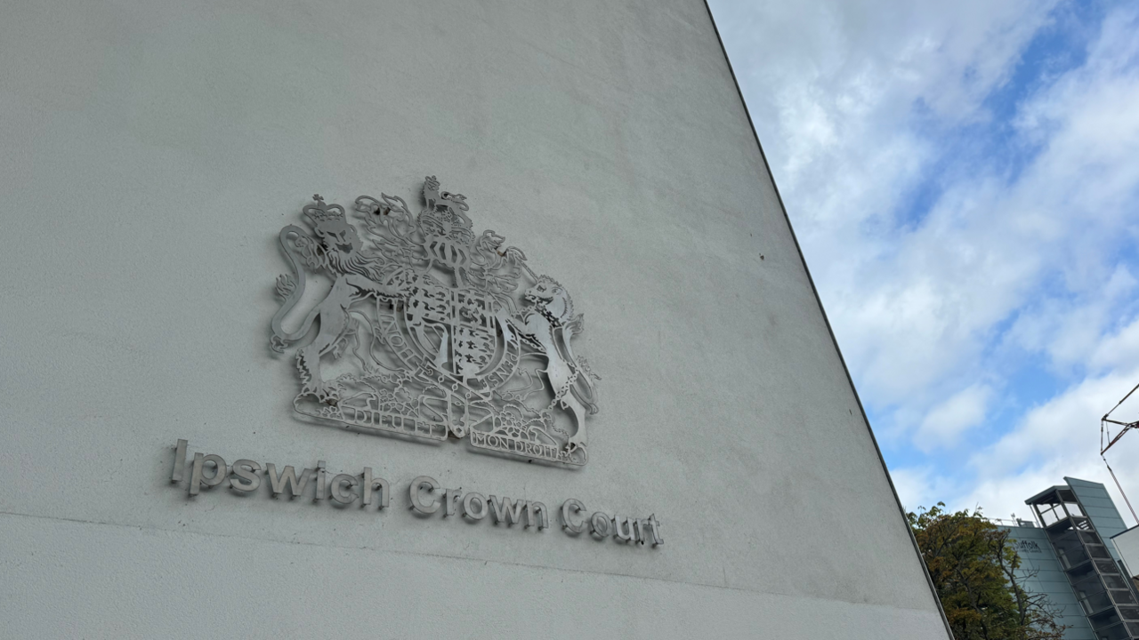 The metal Ipswich Crown Court emblem on a concrete wall.