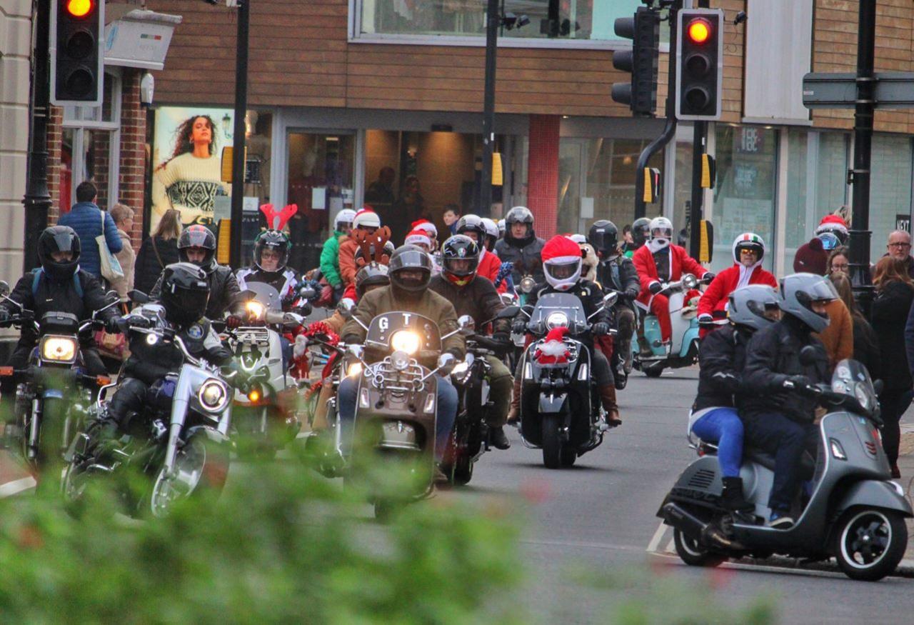 The bikers lining up the streets, dressed in Santa clothes. Their bikes are adorned with Christmas toys and tinsel.