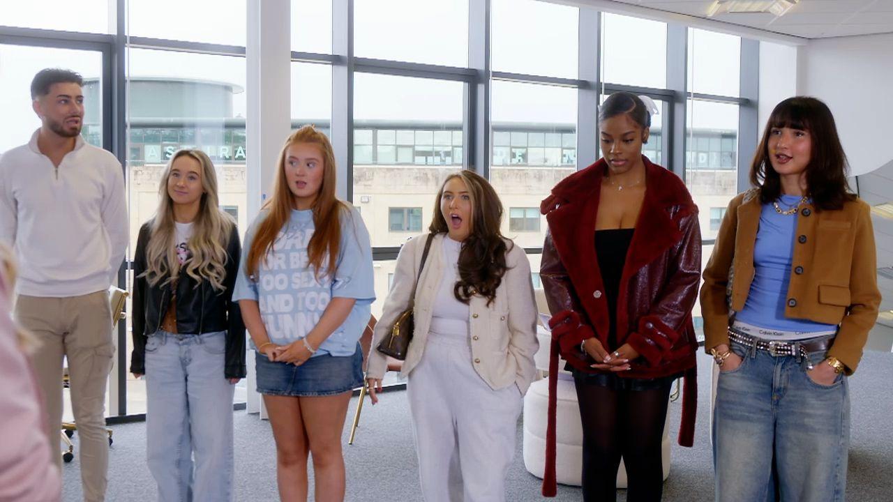 Kira (third from left in a denim skirt and pale blue t-shirt) stands in a line in a big room with a wall of windows. The other TikTokers - Ryan (in white quarter zip top and chinos), Toni (in jeans and a leather jacket), Livi (in a white t-shirt and trousers and a cream jacket), Erica (with  burgundy fur-lines leather jacket, black t-shirt and leggings) and Aicha (baggy jeans, purple t-shirt, tan cropped jacket), stand in line with her.