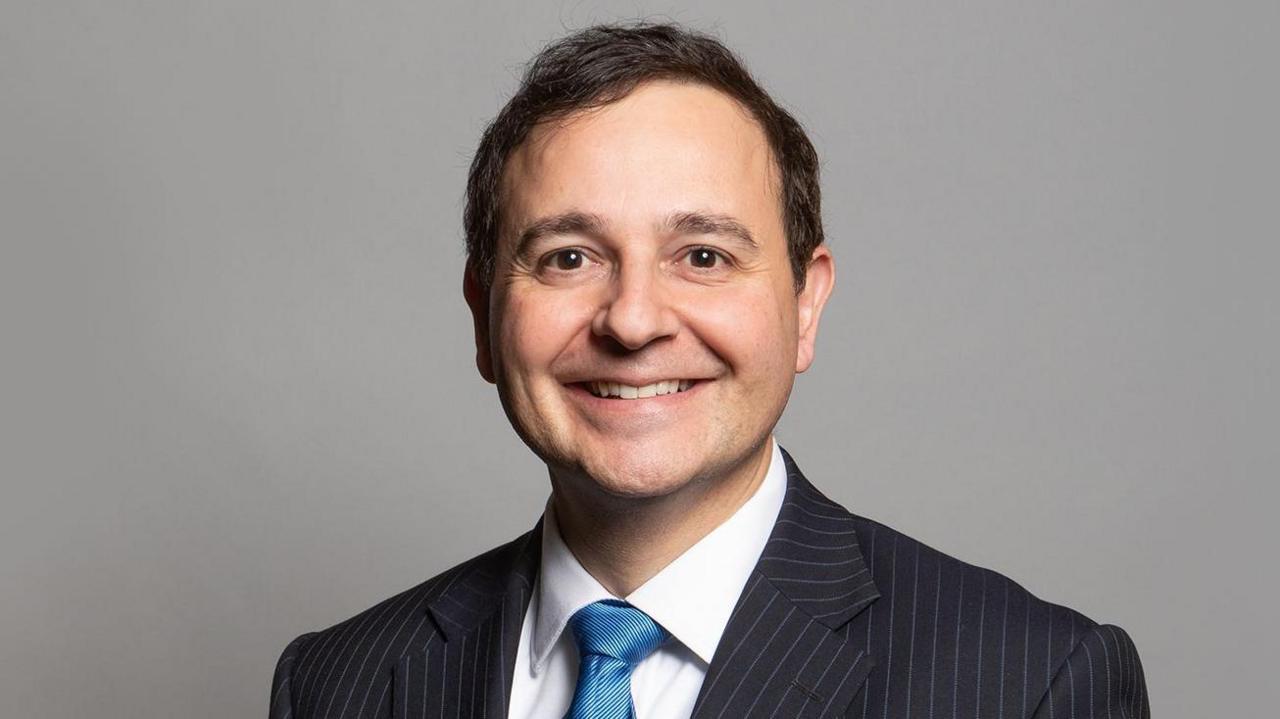 MP in shirt, tie and suit smiling for the camera