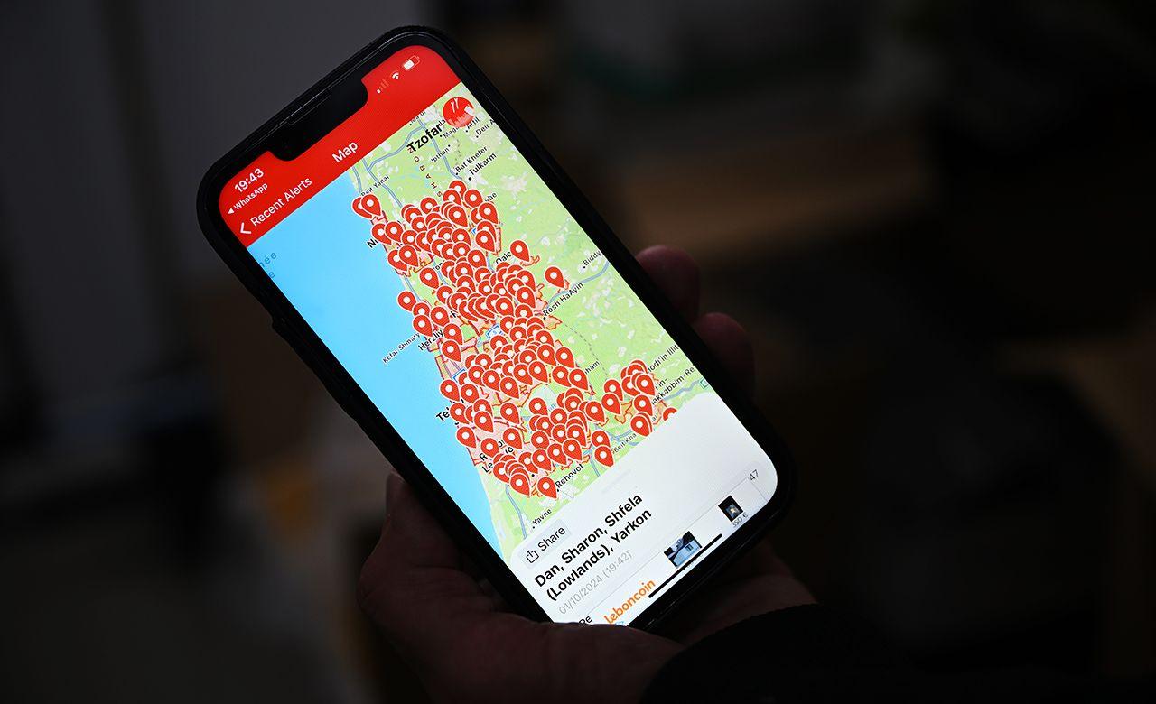 A phone screen is seen held in someone's hand, which shows the Tzofar mobile app displaying lots of red arrows on a map of Israel, meaning there are red alert sirens in place across the country, taken in Tel Aviv on 1 October