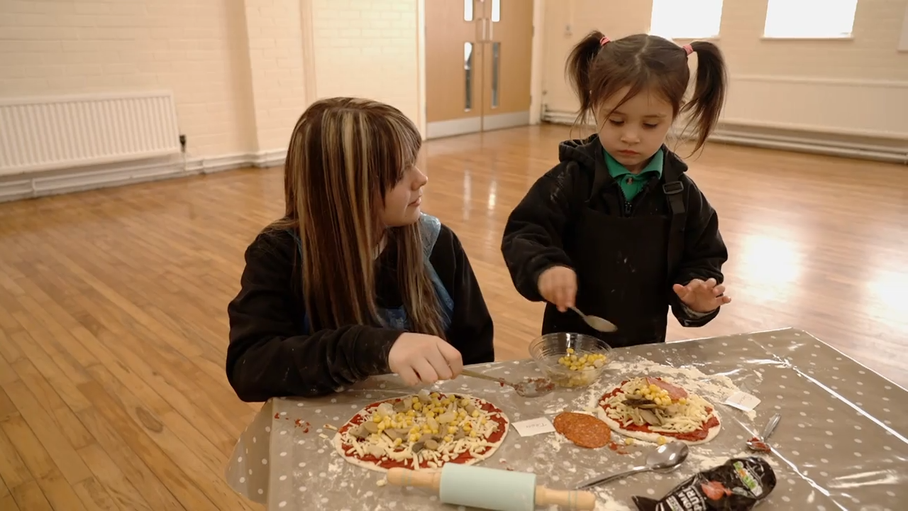 A teenage girl and toddler making pizza together