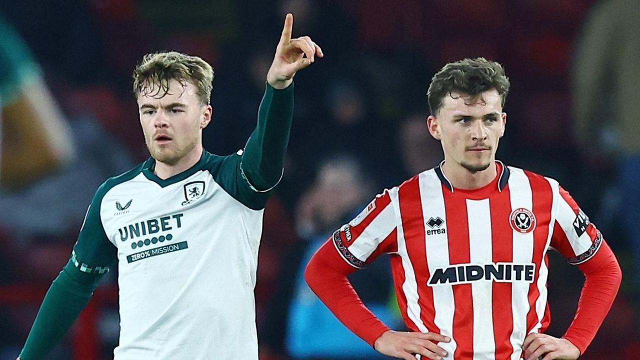 Tommy Conway (left) has his left arm in the air in celebration after scoring as defender Harrison Burrows has his arms on his hips 