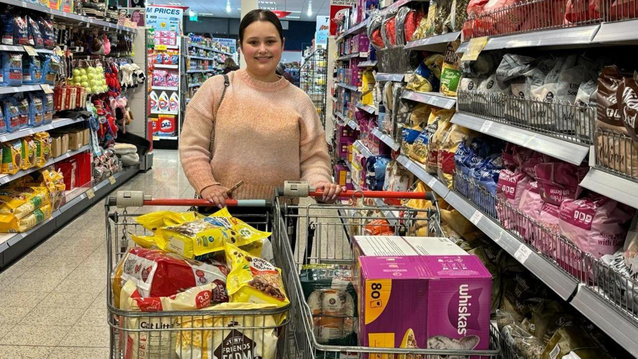 A picture of the founder of A Helping Paw at the supermarket with two trolleys full of pet food 