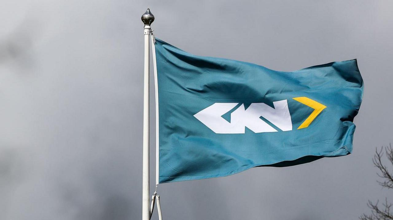 A teal flag on a white pole with the letters GKN in white lettering