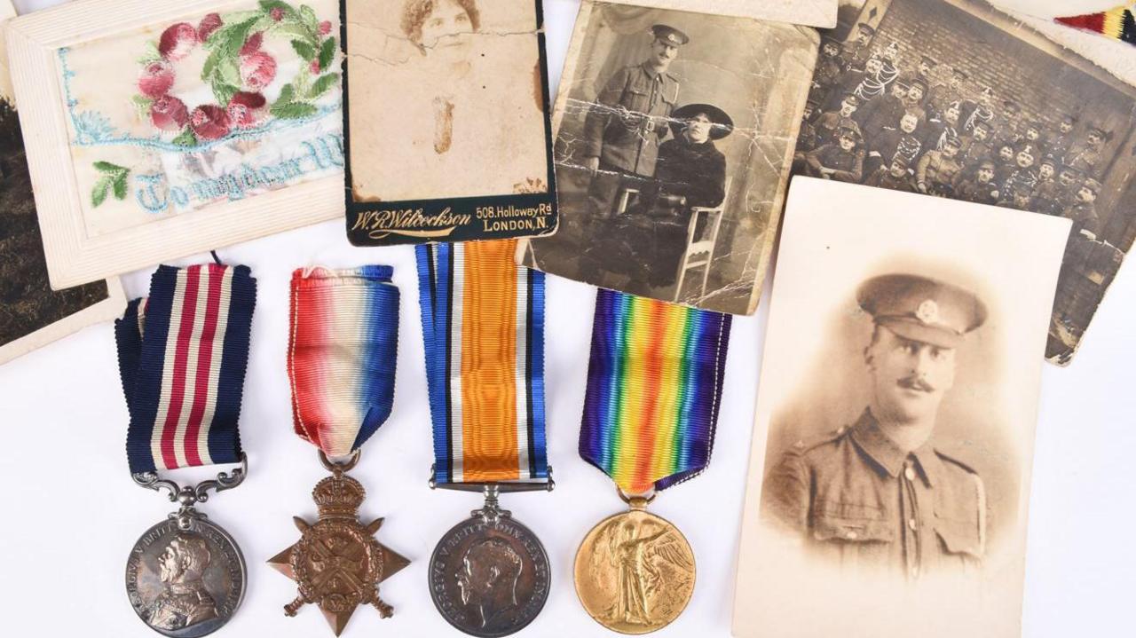 A collection of four metal medals, three of them circular and the fourth star-shaped, on multi-coloured ribbon, alongside a collection of four black and white photographs and a floral print.