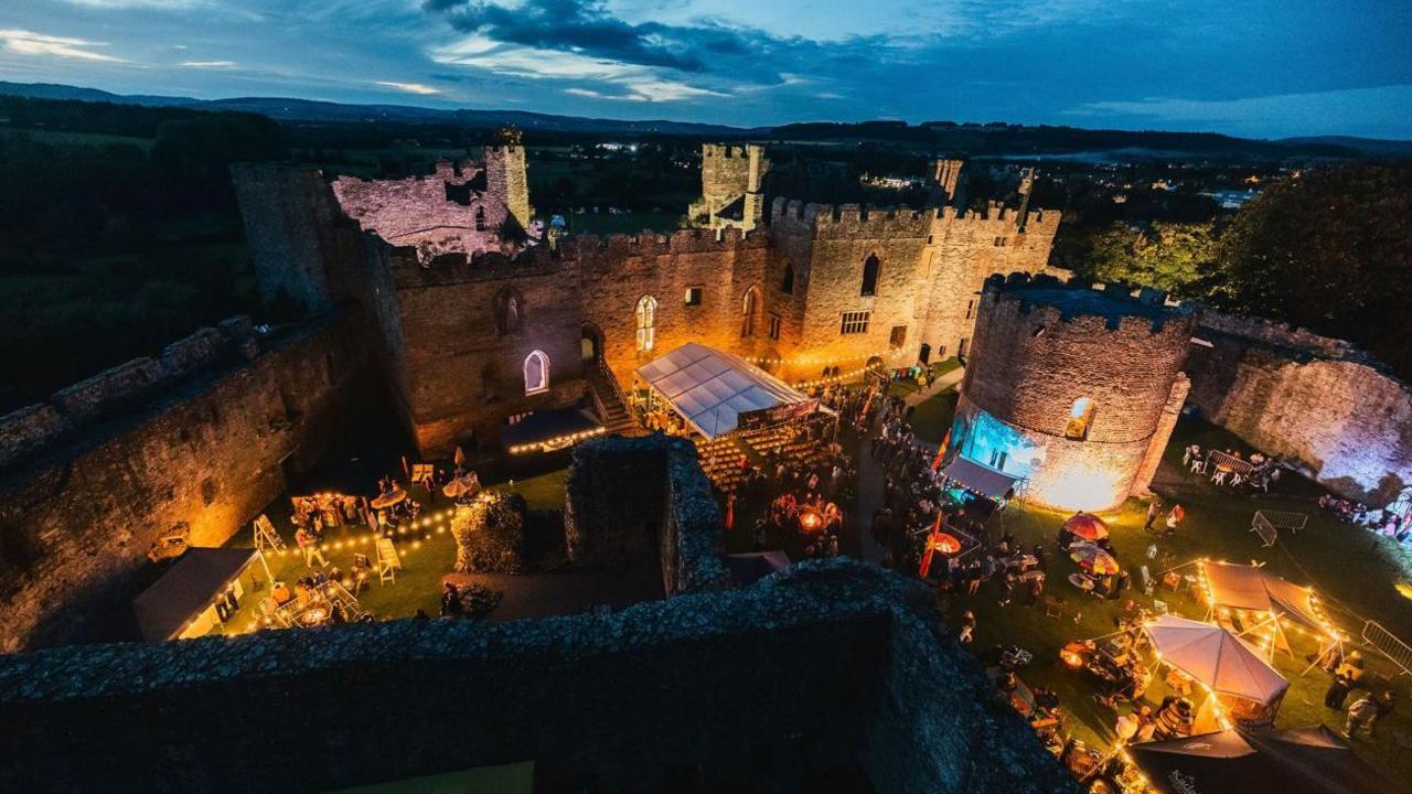 A aerial view of a castle with a number of illuminated marquees seen within the walls