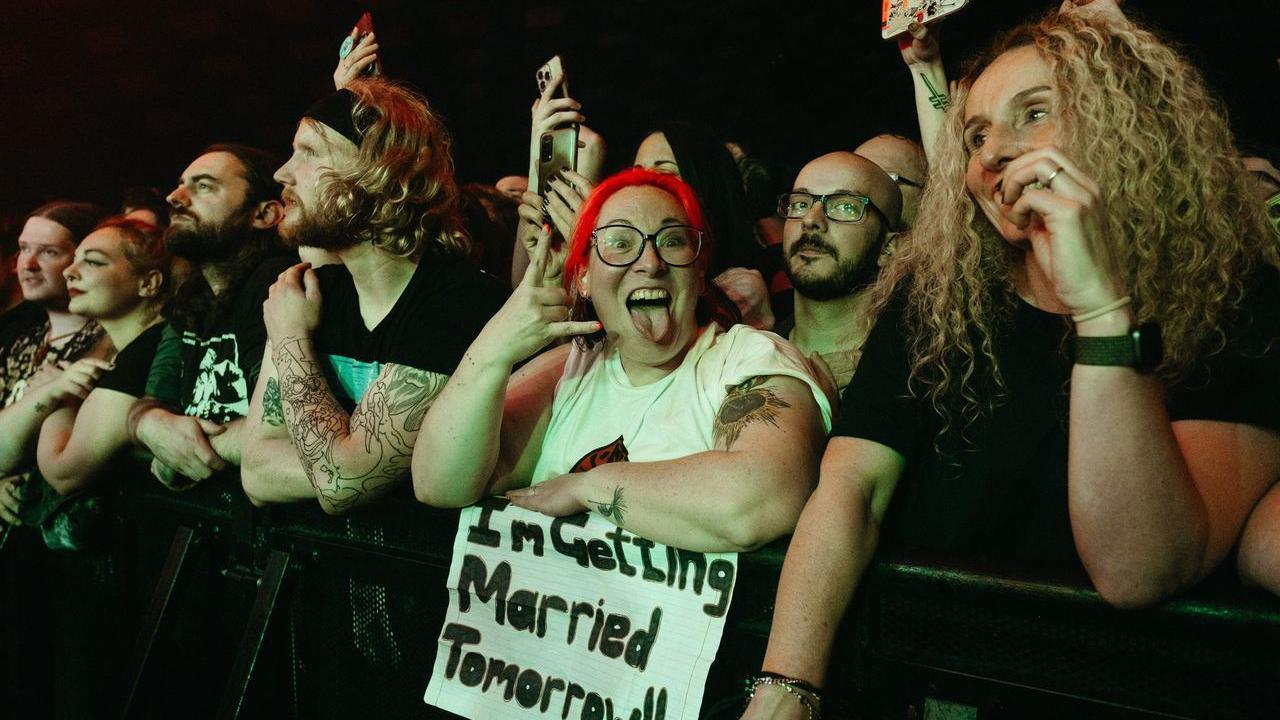 Crowd at the barrier of a concert with a woman holding a banner reading 'I'm getting married tomorrow' 