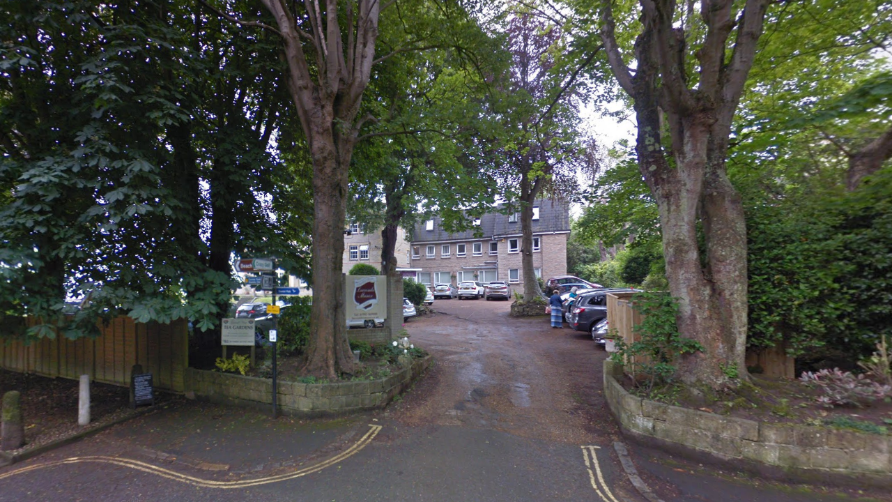 A Google Maps picture of the hotel, a three-storey building seen from a road. Two large trees sit either side of the entrance road