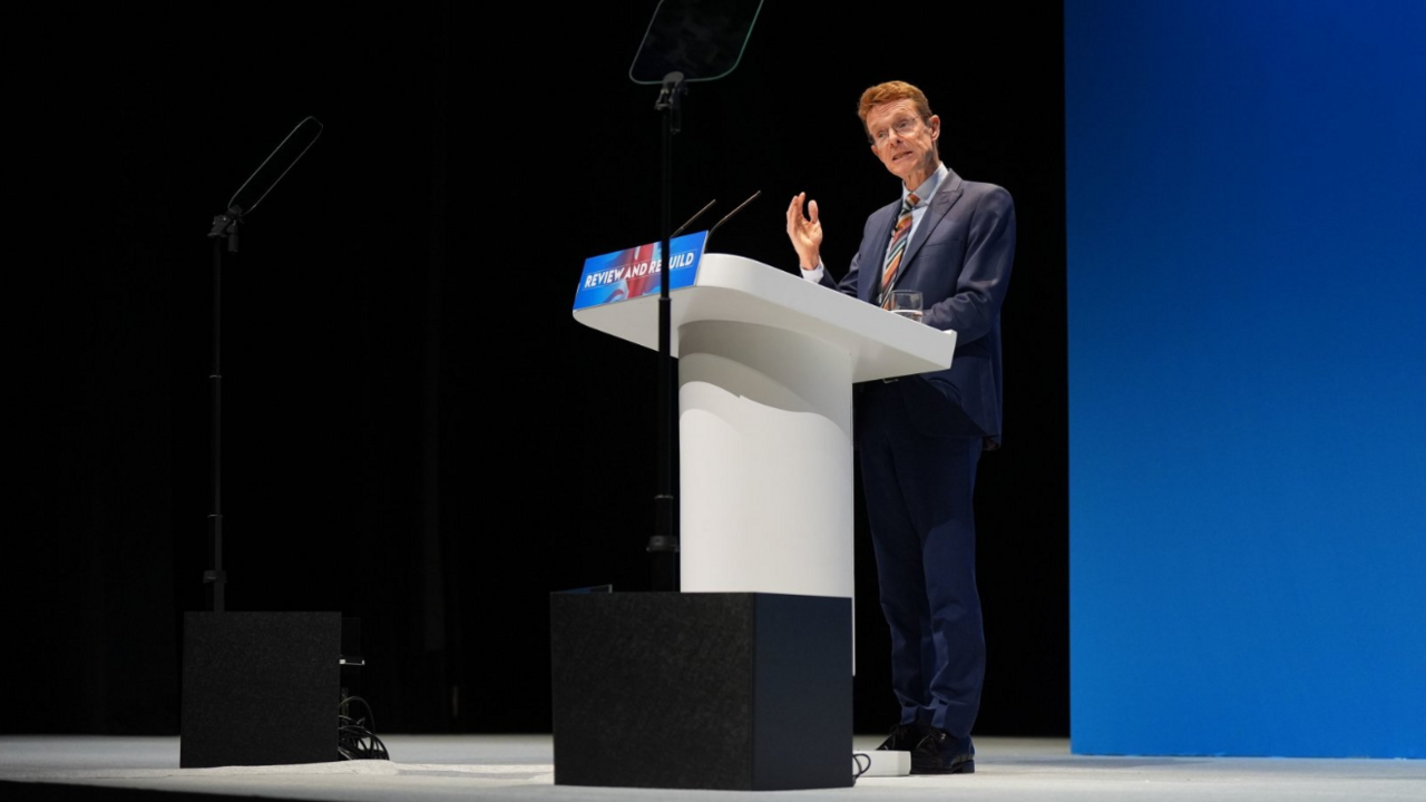 Andy Street in a blue suit stands gesticulating at a podium