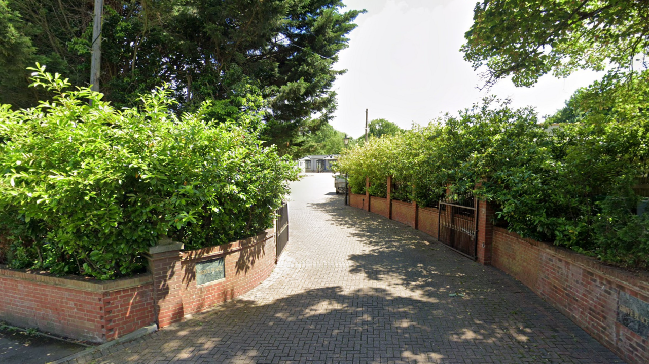 A leafy road with brick walls leads into a cul-de-sac 