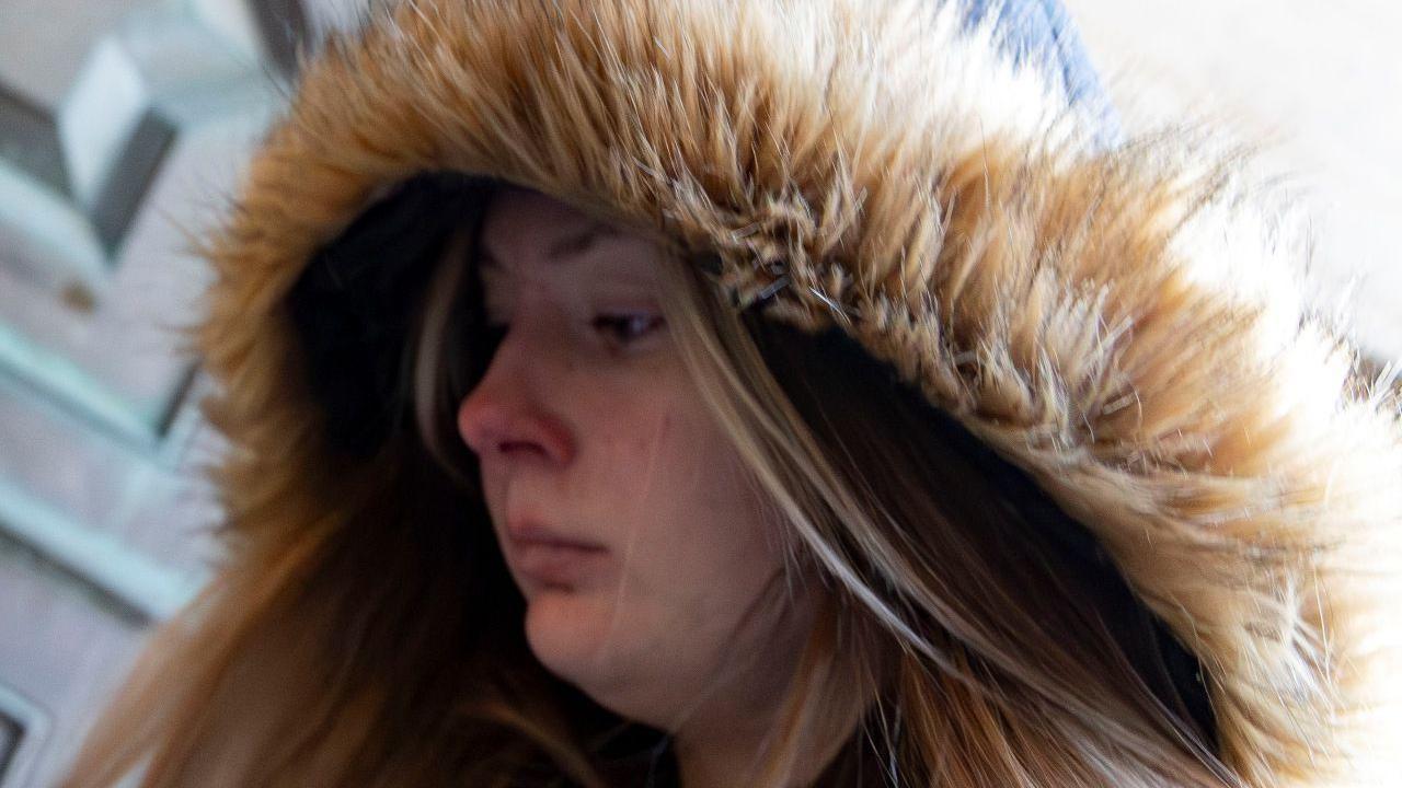 A young woman with a fur-lined hood enters a court building