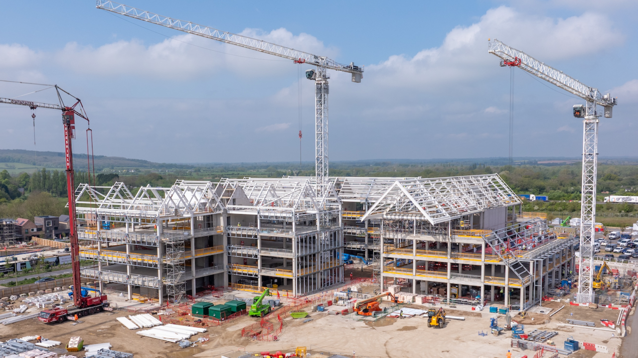 Three large steel structures with three cranes in front of them