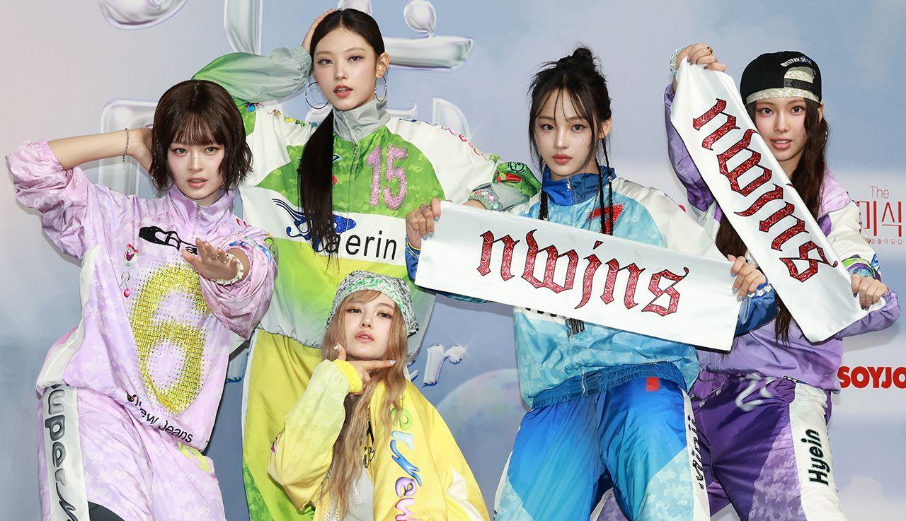 The five members of the K-pop music group NewJeans pose for the camera while wearing tracksuits and holding banners that say 'nwjns', pictured at the SBS Music Awards Summer at INSPIRE Arena in Jung-gu on July 21, 2024 in Incheon, South Korea.