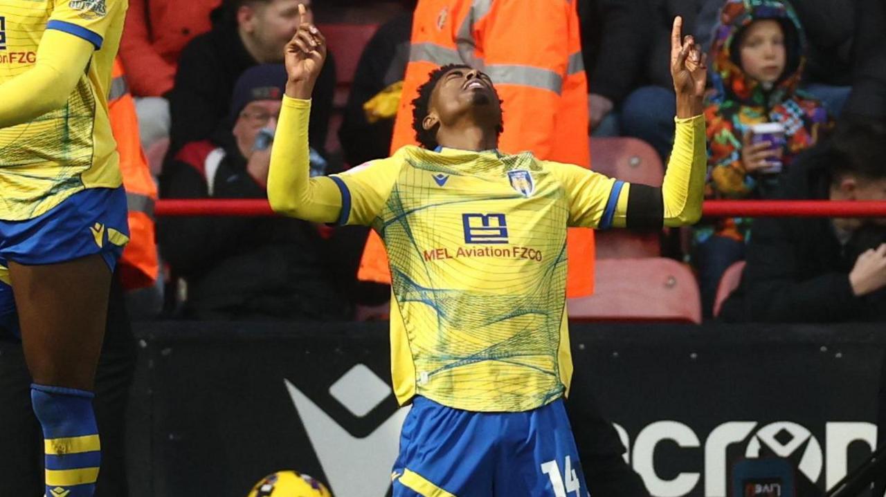 Colchester goalscorer Kyreece Lisbie celebrates by raising two hands into the air