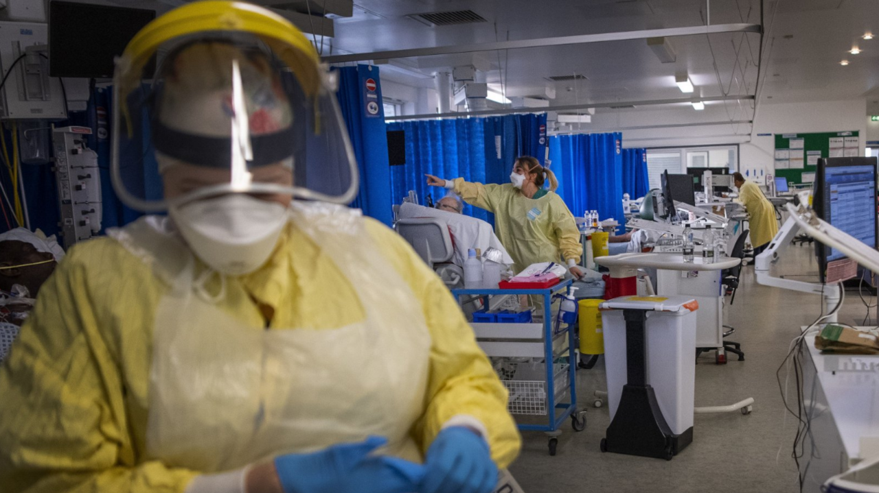  A nurse wearing yellow PPE working on a patient in the ICU (Intensive Care Unit) of a hospital during the pandemic.