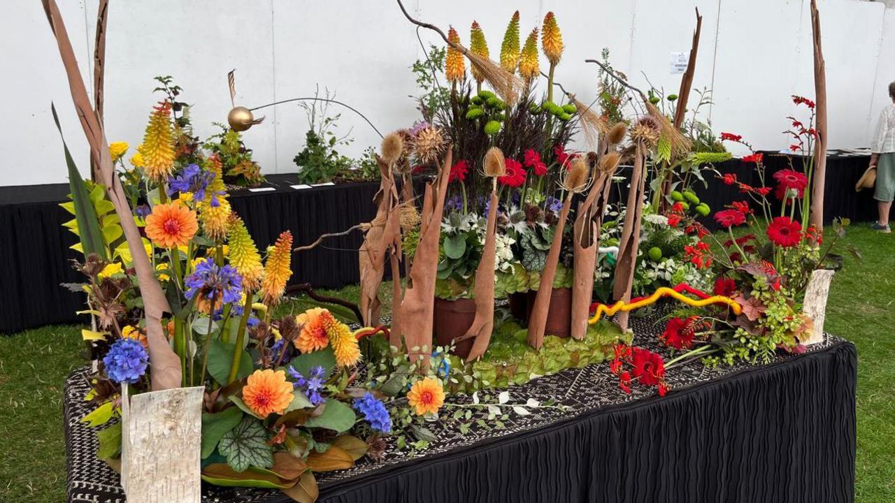 A large floral display on a black table inside a marquee