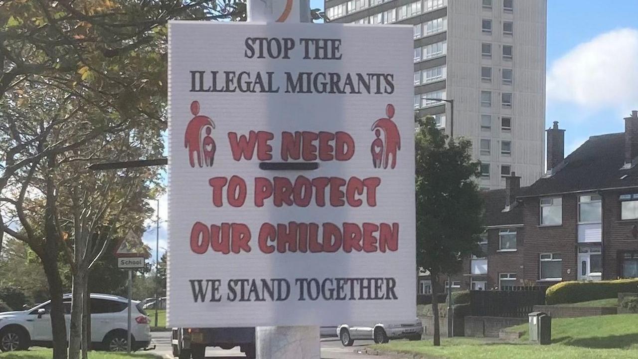 Racist poster on a pole in the Rathcoole estate - the poster reads "stop the illegal immigrants. We need to protect our children. We stand together."