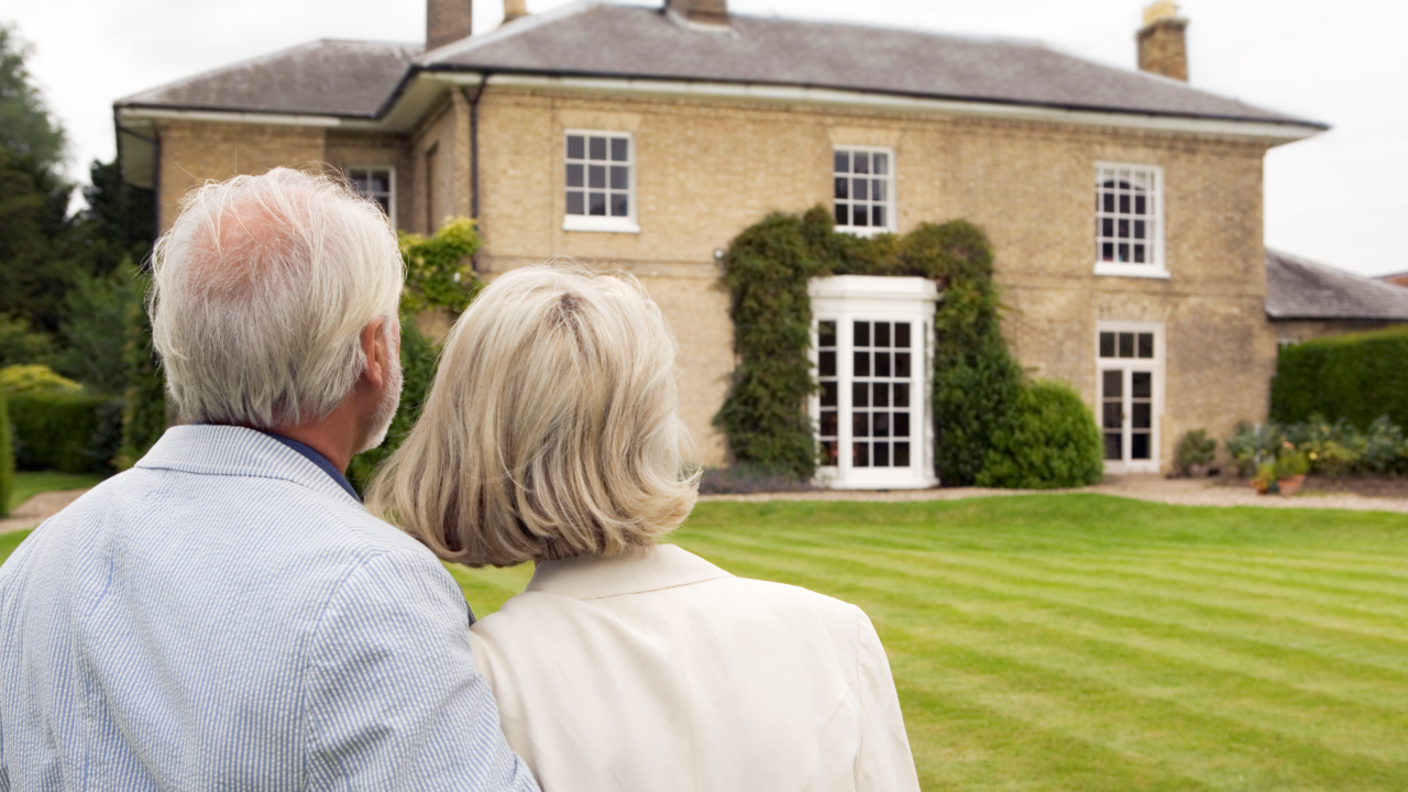 An older couple looking at a large country house