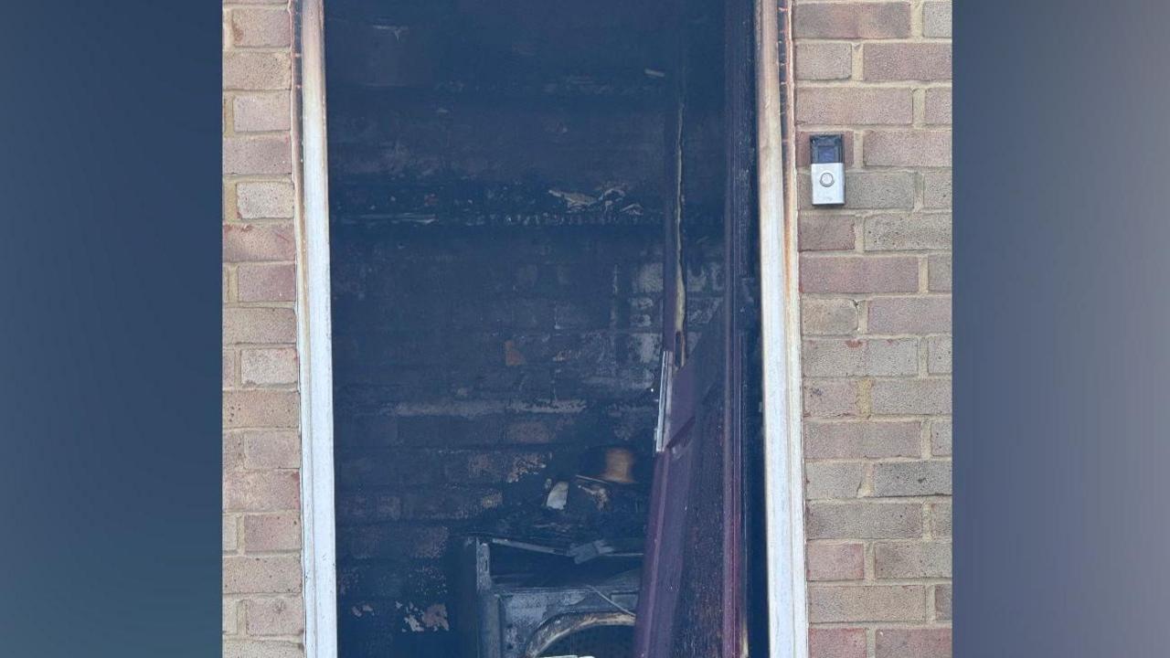 A close-up of a door to a room that appears badly damaged.