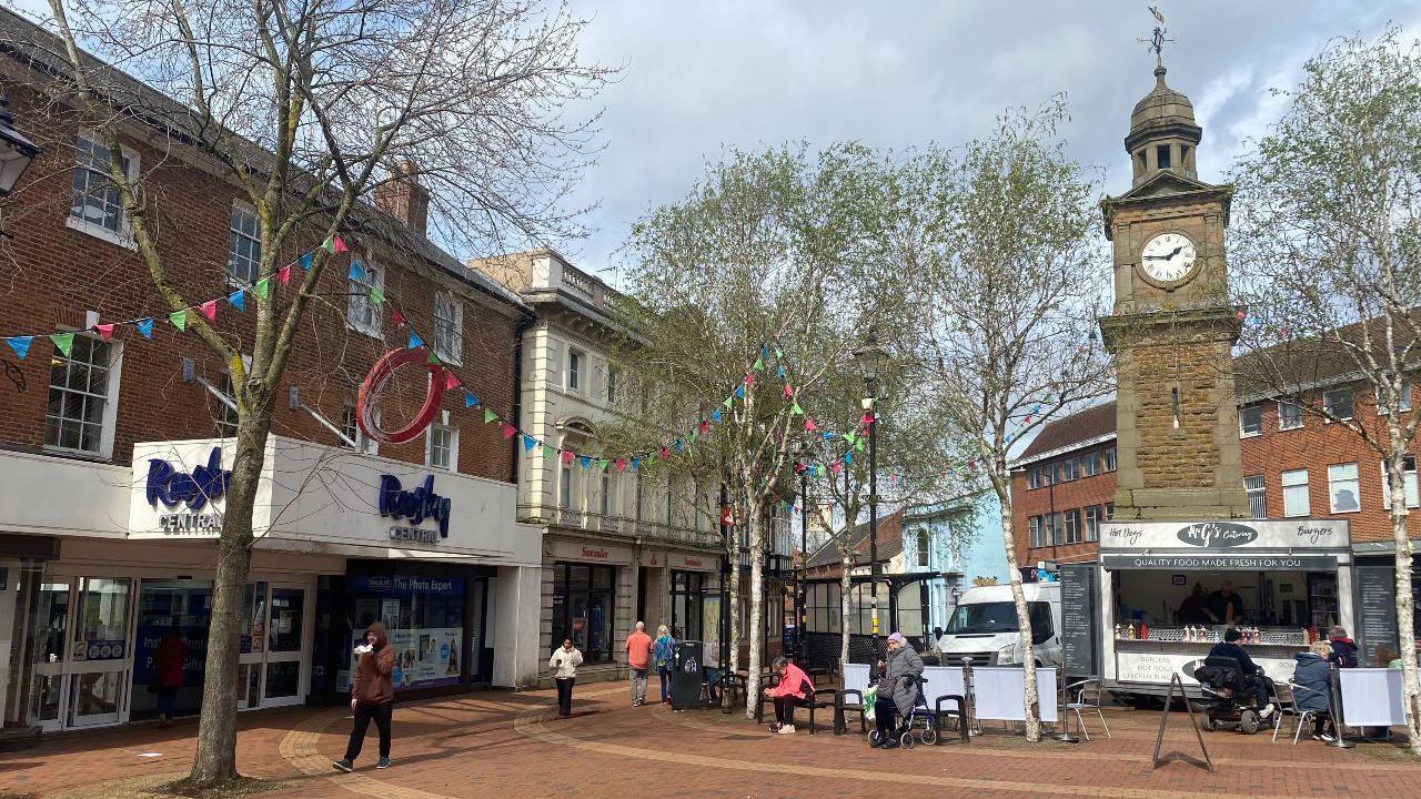 Rugby town centre, with shops, colourful bunting, a stone clock tower and food vans.