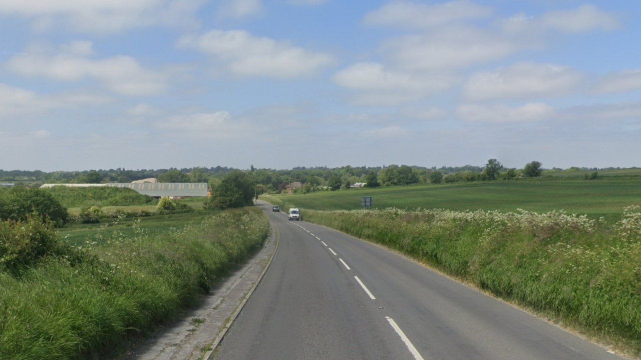 A long stretch of road in between two green fields