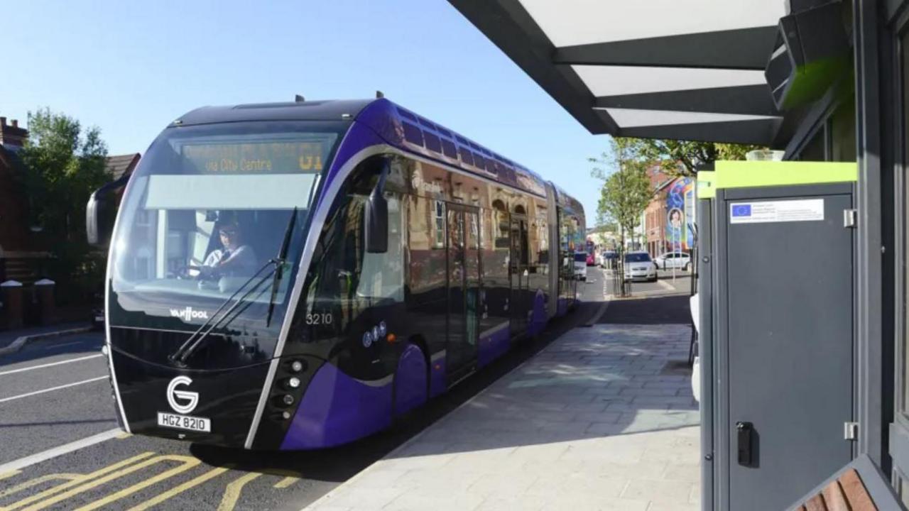 Glider bus pulls into bus stop 