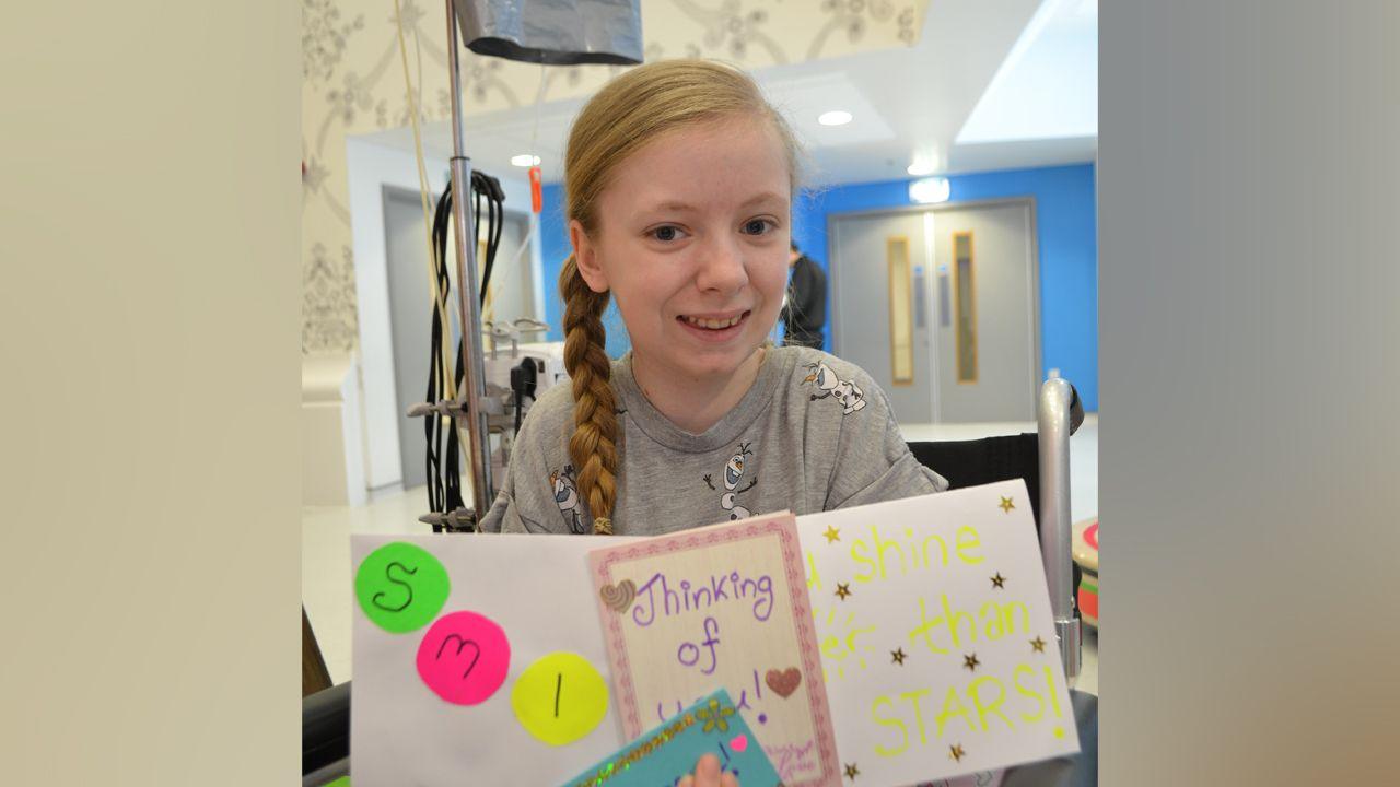 Katie Callaghan as a 13-year-old holding some of the cards she made for others while sat in a hospital.