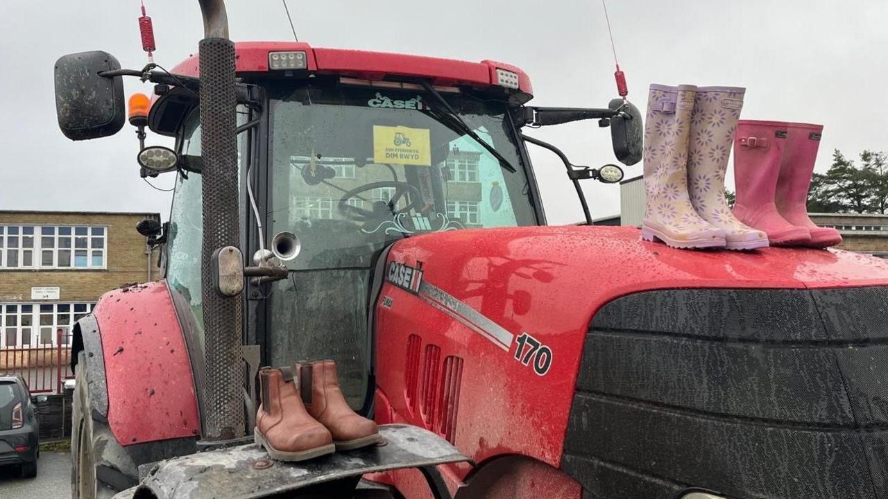 Tractor gydag esgidiau glaw arno wedi'i barcio y tu allan i Ysgol Bro Preseli