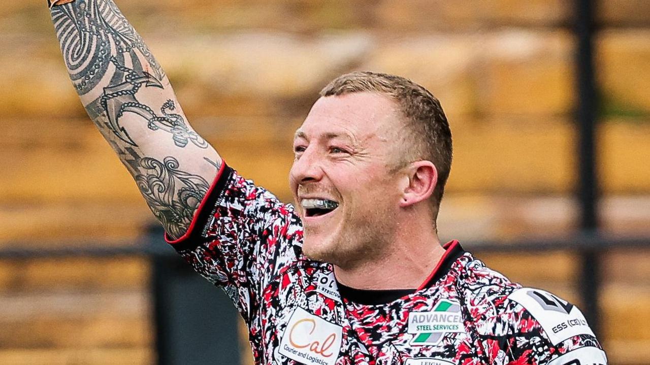 Josh Charnley with his right arm in the air and a big smile on his face after breaking the Super League try-scoring record 