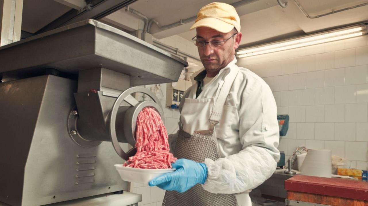 Man feeds meat into grinder