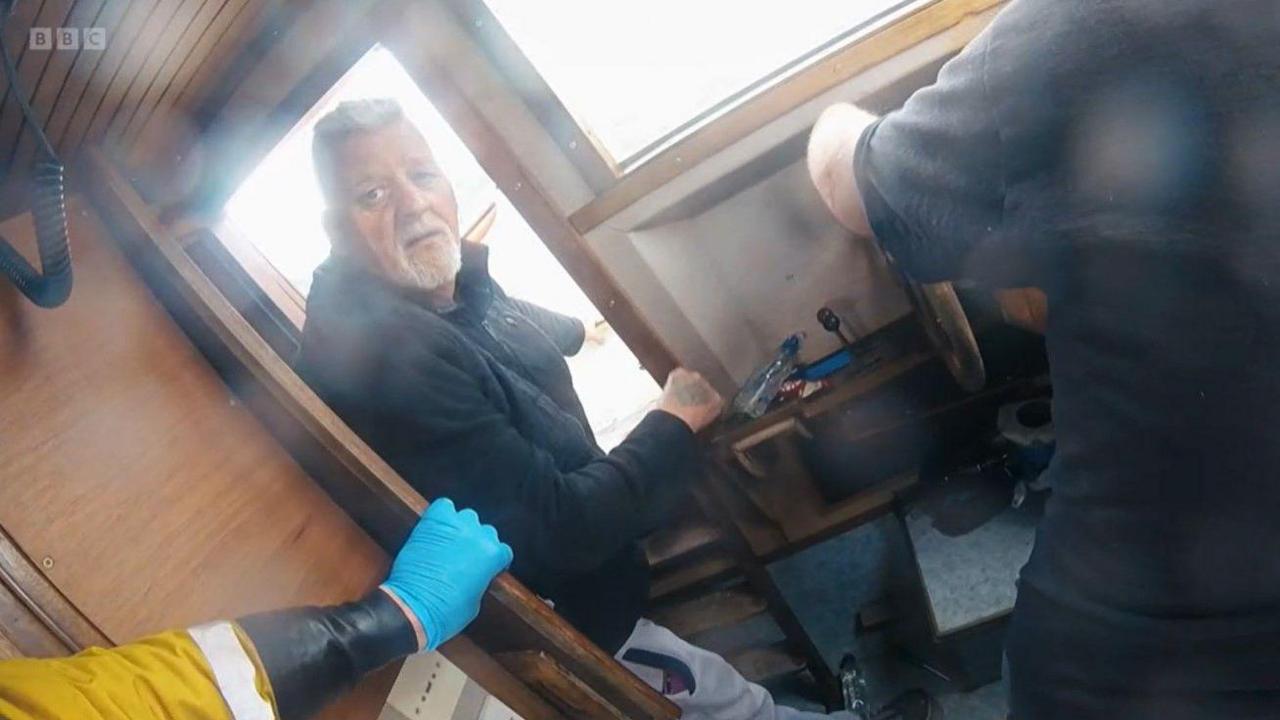 RNLI crew with Glen inside a small fishing boat